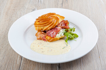 pap with egg benedict bacon cheese sauce on a white plate