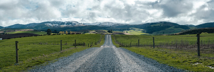 Rural gravel road on a farm, beautiful view of the snowy hills. New Zealand, canterbury
