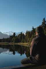 Fototapeta na wymiar Man looking at mountains in Lake Matheson. New Zealand, South Island