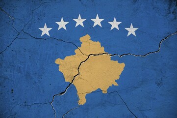An image of the Republika Kosovo flag on a wall with a crack.