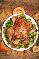 Thanksgiving turkey or chicken for a festive dinner. Food table background with autumn seasonal specialties for Thanksgiving Day. Fried chicken with pumpkin, vegetables and autumn decor on a wooden