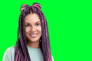 Portrait of a beautiful girl with a hairstyle from pink braids in turquoise clothes isolate on a green background. The concept is modern style, individuality, inclusiveness, creativity.