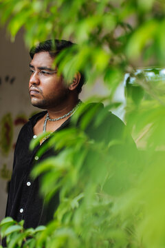 portrait of dark skinned Indian man surrounded by leaves