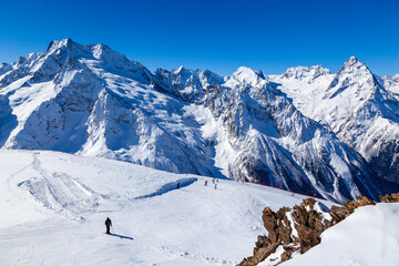 Fototapeta na wymiar Caucasus Mountains, Panoramic view of the ski slope on the horizon in winter day. Dombai ski resort, Western Caucasus, Karachai-Cherkess, Russia.