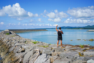 沖縄県小浜島の海人公園の防波堤でガッツポーズする成人男性