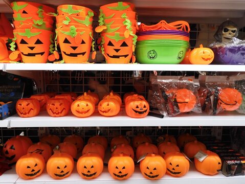 Plastic Halloween pumpkins and felt Halloween buckets on store shelves, along with other items such as a plastic skull or spider web.