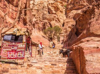Arab man riding a donkey on the Ed-Deir Trail (monastery trail) in the ancient city of Petra,...