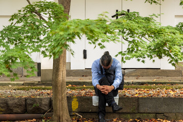 勤務に疲れ境内で仮眠をとる中年の勤め人