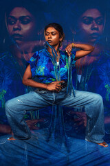 portrait of dark skinned Indian woman from Malaysia against a dark blue background with blue flowers