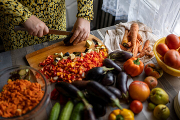 woman in yellow dress prepares vegetables for pickling and wields knife