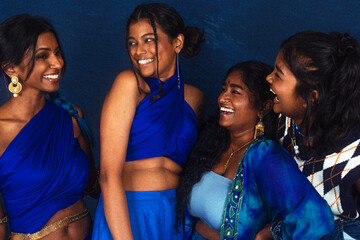 Obraz premium group portraits of dark skinned Indian women from Malaysia against a dark blue background, laughing