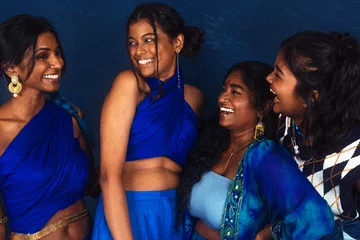 Poster group portraits of dark skinned Indian women from Malaysia against a dark blue background, laughing © Daniel Adams