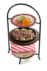 Ternera con ajo y verduras en una torre de bandejas sobre fondo blanco. Beef with garlic and vegetables in a tower of trays on a white background.