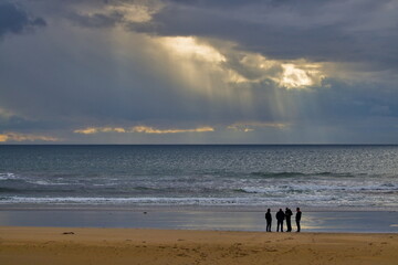 Friends gather on a beach at sunset