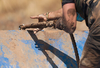 Mud race runners, participant for overcoming barriers through ropes