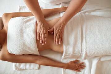 Obraz na płótnie Canvas Slim young woman receiving stomach massage in spa salon