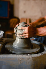 Close-up of the hands of the craftsman while creating a ceramic pot on the lathe