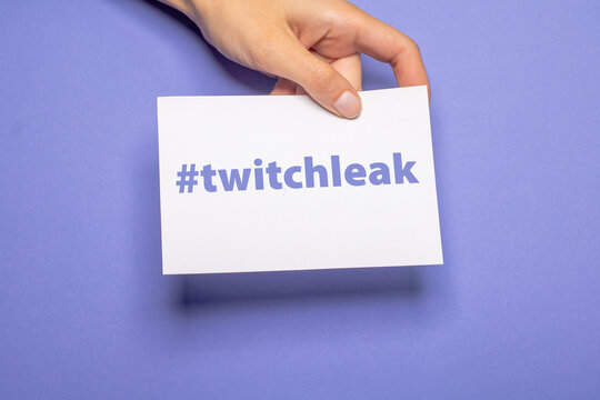 female hand holds a piece of paper with the hashtag twitchleak in violet writing over violet background cardboard