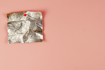 Empty candy wrapper pinned to pink background. Rectangular piece