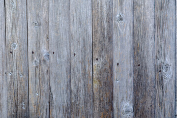 An old wooden wall. Weathered, cracked boards nailed down with r