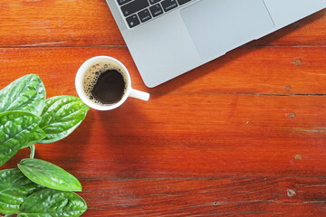 Coffee and laptop on wooden desk.