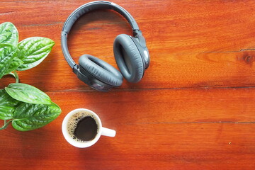 Headphones  and coffee on wooden desk table.