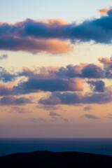 Stunning seascape with some fluffy clouds on an orange sky during a beautiful sunrise. Sardinia, Italy.