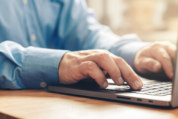 Male hands typing on a laptop keyboard, close-up view