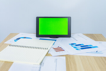 green screen on tablet near graph document for making presentation