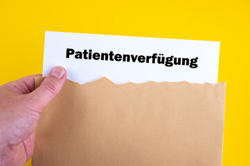 Eine Hand nimmt eine Patientenverfügung aus dem Umschlag