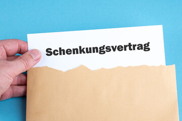 Eine Hand nimmt einen Schenkungsvertrag aus einem Briefumschlag
