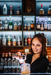 Portrait of young attractive woman bartender Making Cocktail in bar