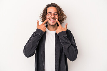 Young caucasian man isolated on white background smiles, pointing fingers at mouth.