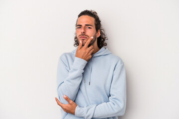 Young caucasian man isolated on gray background suspicious, uncertain, examining you.