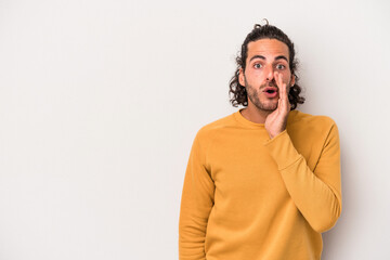 Young caucasian man isolated on gray background is saying a secret hot braking news and looking aside