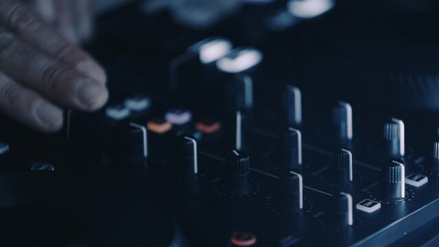 Dj mixing music with midi controller device on stage in night club. Professional disc jockey mixes electronic musical tracks in close up video clip