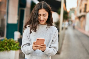 Young middle east girl smiling happy using smartphone at the city.