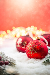 Christmas red decorations on snow with fir tree branches and christmas lights. Winter Decoration Background