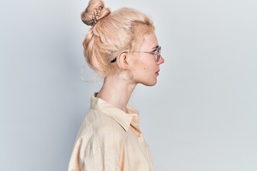 Beautiful caucasian woman with blond hair wearing casual look and glasses looking to side, relax profile pose with natural face with confident smile.