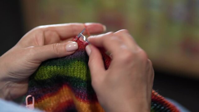 Womens hands knit woolen color sweater with knitting needles. Top view, close-up of hands and knitting
