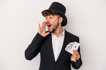 Young arab wizard man holding a magic cards isolated on white background shouting and holding palm near opened mouth.