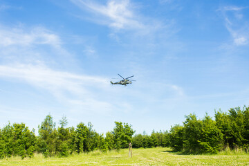 helicopter is flying on blue sky, green ground under it