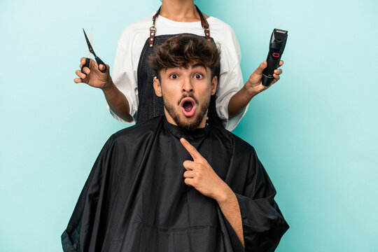 Young Arab Man Ready To Get A Haircut Isolated On Blue Background Pointing To The Side