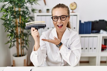Young caucasian woman holding teeth whitening palette pointing aside with hands open palms showing copy space, presenting advertisement smiling excited happy