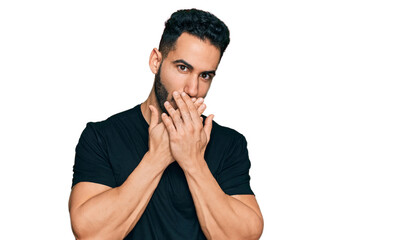 Hispanic man with beard wearing casual black t shirt shocked covering mouth with hands for mistake. secret concept.