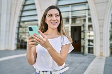 Young hispanic woman smiling confident using smartphone at street