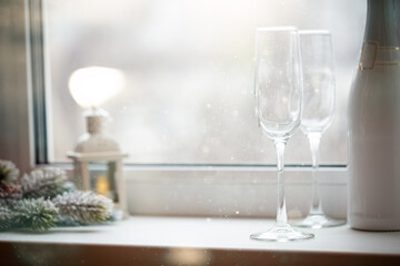 Empty crystal glasses and a bottle of champagne in front of the window. Concept of new year and Christmas holidays.