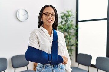 Fototapeta na wymiar Young african american woman smiling confident injury on arm at clinic waiting room