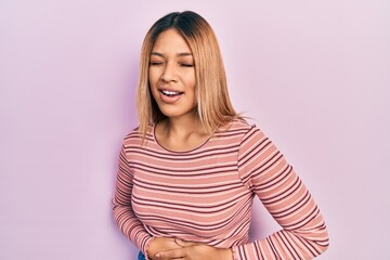 Obraz premium Beautiful hispanic woman wearing casual striped sweater with hand on stomach because nausea, painful disease feeling unwell. ache concept.