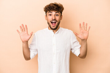 Fototapeta premium Young arab man isolated on beige background receiving a pleasant surprise, excited and raising hands.